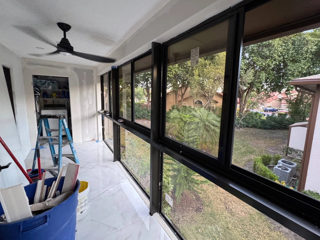 An indoor room with white walls and marble floors, featuring a long horizontal window overlooking a green yard.